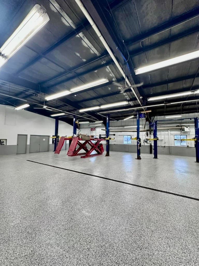 Large facility shop with vehicle lifts over a gray flake floor — Central New York