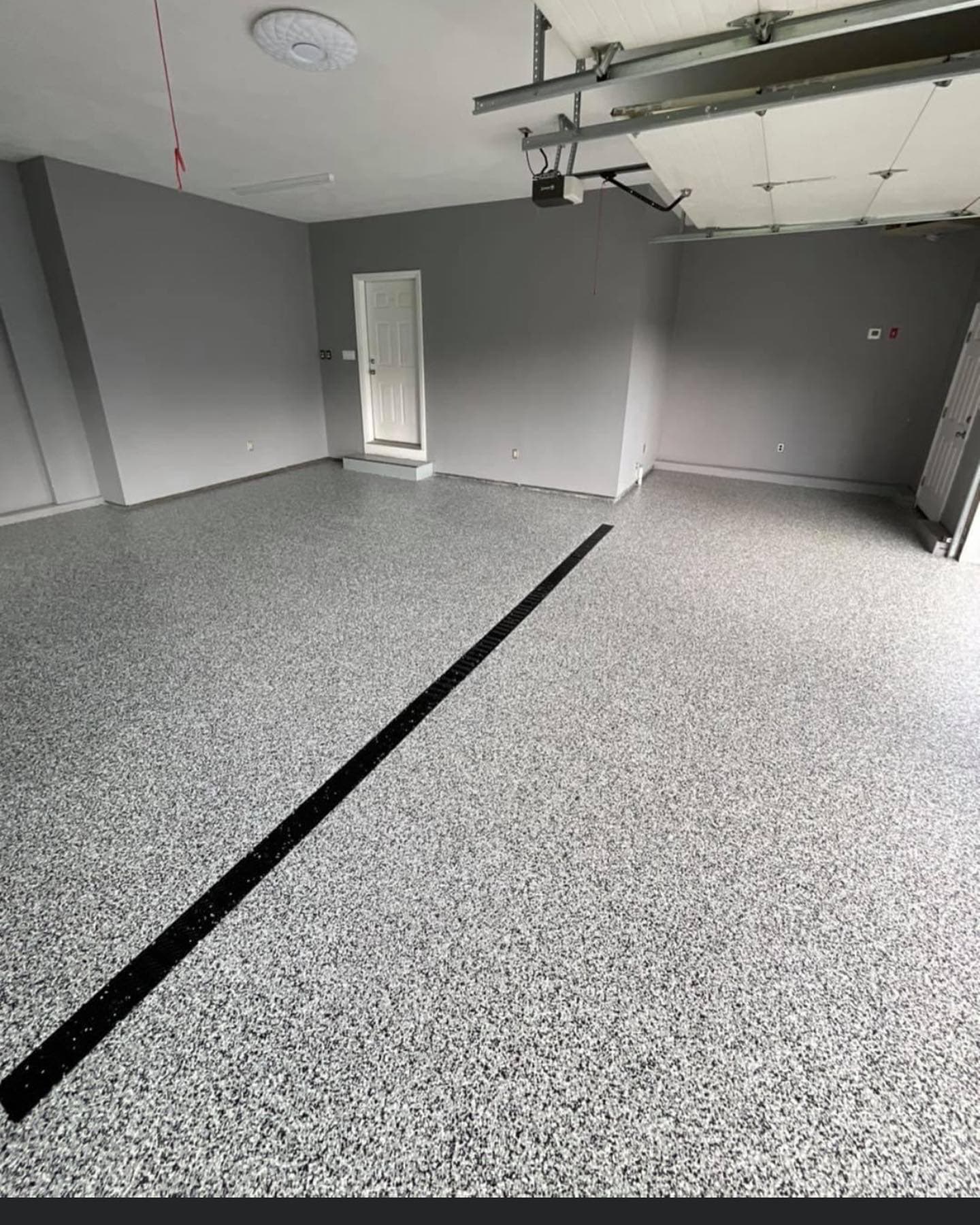 Gray and white full-flake garage floor with a black trench drain, Central New York