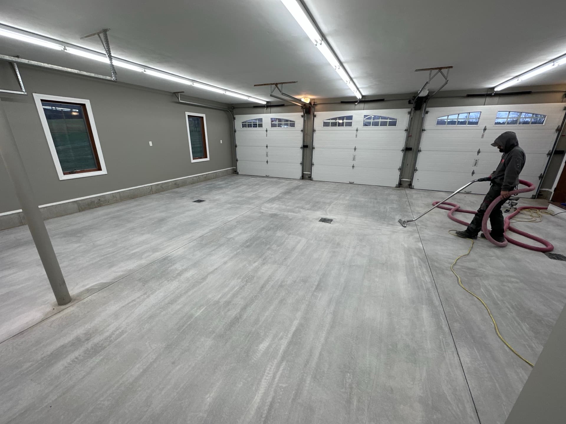 Crew diamond-grinding a three-car garage floor to prep it for coating, Central New York