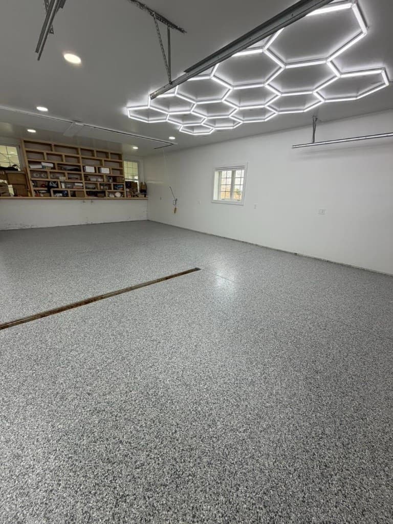 Finished garage with a gray and white full-flake floor and hexagon LED lighting after Nick's Concrete Coating